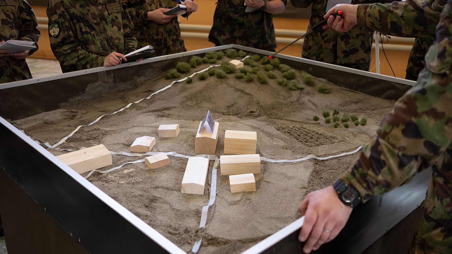 Sandkasten mit Gebäudeattrappen aus Holz.