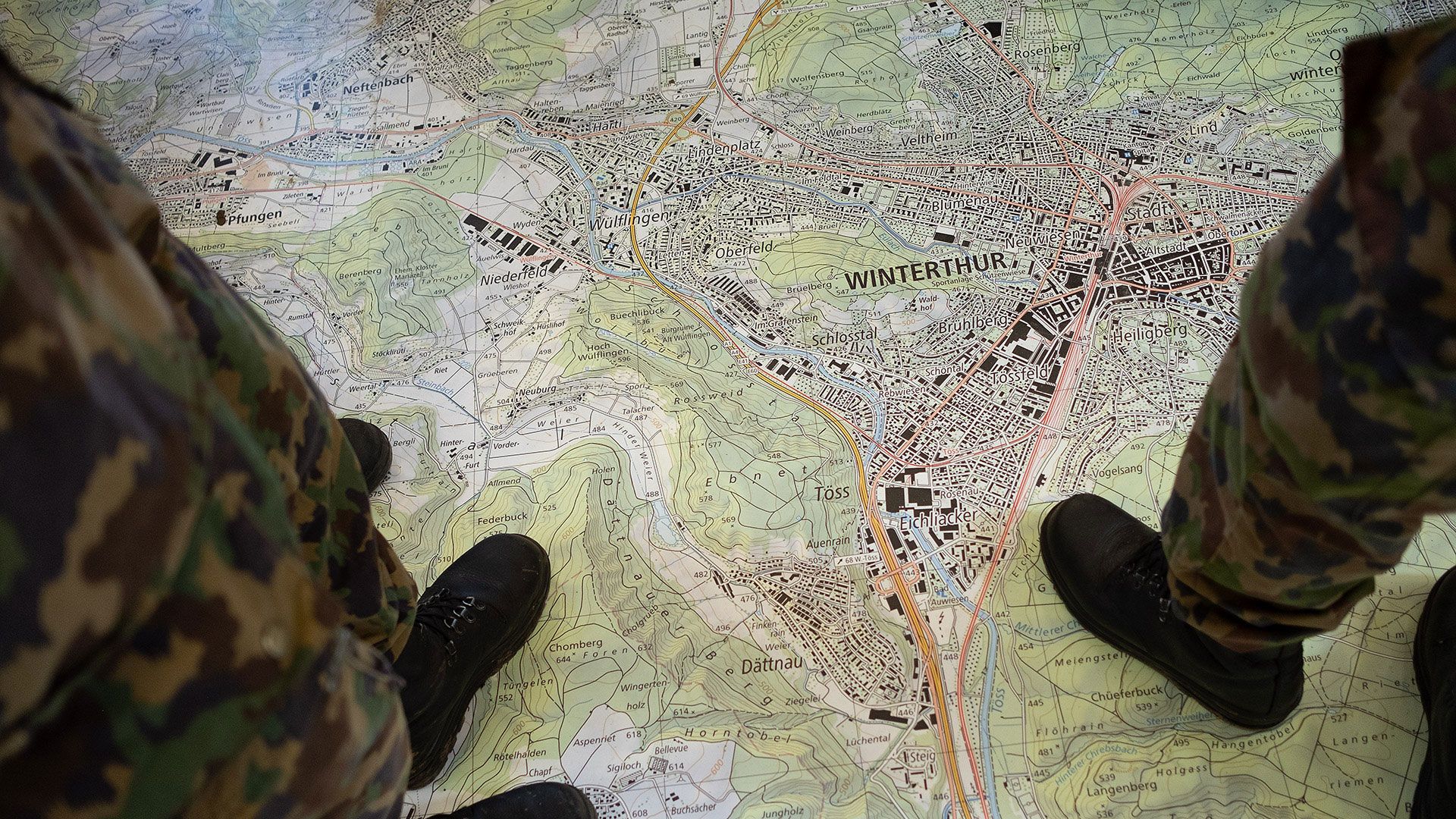 Aspirantes et aspirants en bottes de combat sur la carte géographique surdimensionnée.